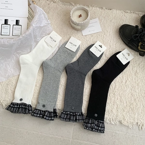 Close-up of retro mid-calf socks with plaid ruffles and buttons on soft carpet
