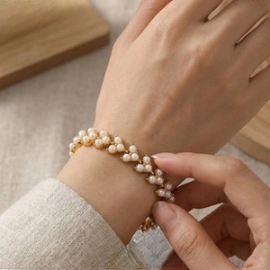 Detailed shot of an elegant gold V-shaped pearl bracelet worn on a female wrist