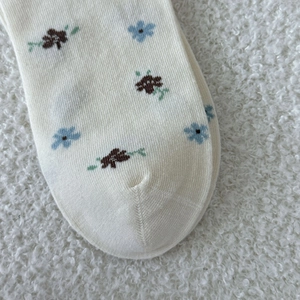 Gros plan de la couture plate sur des chaussettes blanches à fleurs au style doux