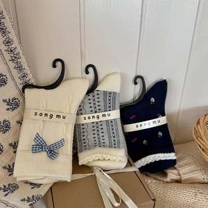 Détail de chaussettes mi-mollet en coton avec fleurs marines et nœuds à carreaux