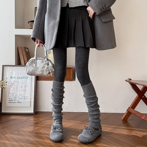 Detail of dark grey knitted leg warmers styled with a black pleated skirt and wool coat