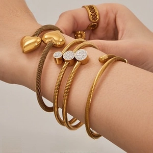 Close-up of a 18K gold plated woven heart bracelet and ring set on a fashion model