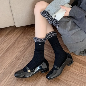 Detail of JK style mid-calf socks with plaid ruffle trim and Mary Jane shoes on wood floor