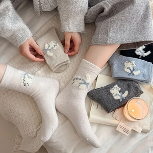 Detail of knit socks featuring cute cat embroidery and blue bow accents in winter wool
