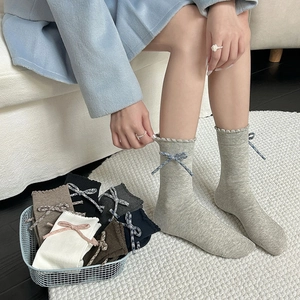Close-up of ribbed cuffs with scalloped edges and small plaid bows on cotton socks