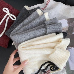 Vue détaillée de jambières en tricot avec nœuds à lacets et poignets côtelés en plusieurs couleurs