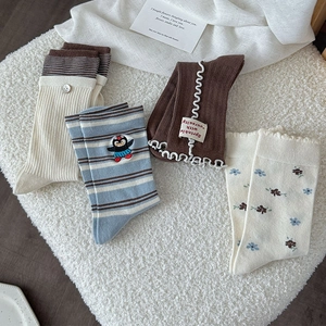 Détail de quatre chaussettes mi-mollet à fleurs avec broderie et volants sur fond doux