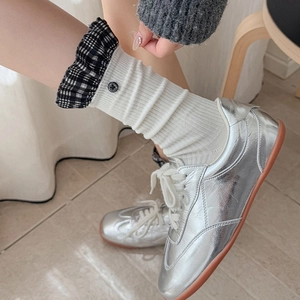 Detail of white ribbed socks with black and white plaid ruffled cuffs and button
