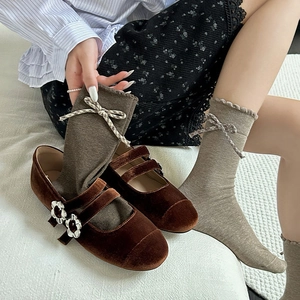 Detail of vintage brown socks with ruffle edges and plaid bows worn with Mary Jane shoes