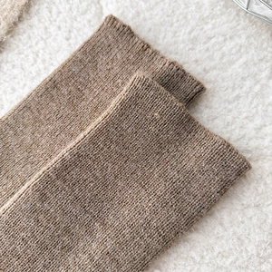 Macro shot of brown ribbed knit leg warmers with thick texture on white faux fur background