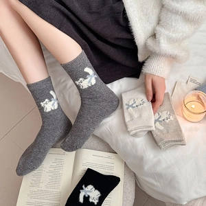 Detailed knit texture of wool cat socks with blue bow patterns in neutral colors