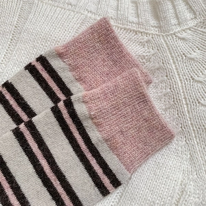 Detailed view of thick striped wool socks with pink ribbed cuffs and knit texture