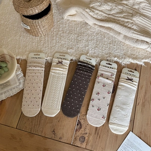 Close-up of five pairs of vintage knit mid-calf socks with floral and bow patterns
