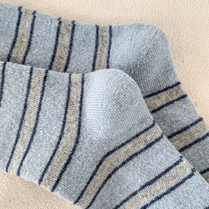 Détail de chaussettes rayées avec motifs bleu et gris sur un tissu en coton doux