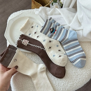 Détail de quatre paires de chaussettes à fleurs et rayures avec volants et broderie