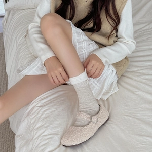 Close-up of cream faux shearling Mary Janes paired with ribbed mid-calf socks