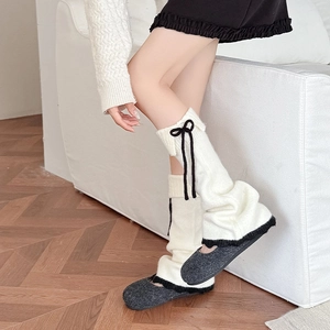 Détail de jambières en tricot avec nœuds en ruban noir et bordure contrastée crème