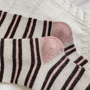 Close-up of striped wool socks featuring pink heel detail and soft knitted texture