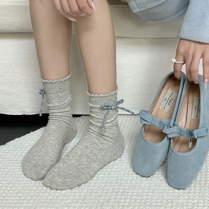 Detail of gray knit mid-calf socks with wavy edges and blue plaid bow decoration