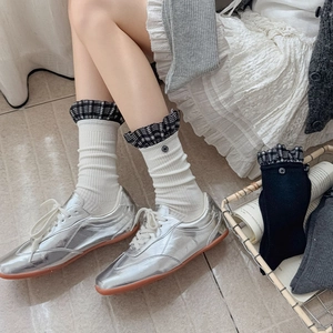 Close-up of white crew socks with plaid ruffle trim and button detail on the cuff