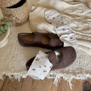 Detailed close-up of dark brown Mary Jane shoes paired with floral knit crew socks