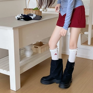Detail of white lace trim socks with red letter A embroidery and black platform boots