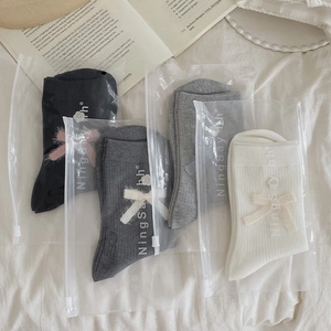 Detail view of four-pair mid-calf socks set with bows and shell buttons in pastel tones