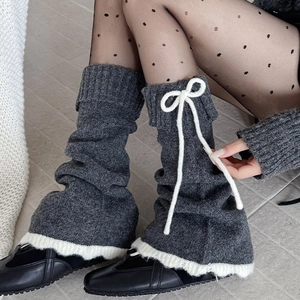 Détail de jambières en tricot gris avec bordure en dentelle blanche et nœud réglable