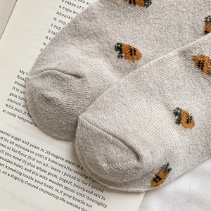 Gros plan de chaussettes en maille avec motif de carotte sur un fond gris clair
