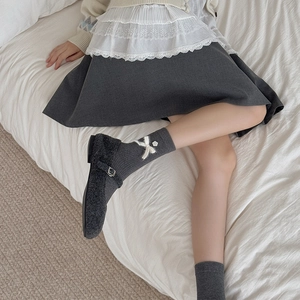 Close-up of grey knit mid-calf socks with white bow paired with Mary Jane shoes