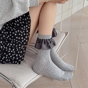 Details von grauen Ballettsocken mit Rüschenrändern und schwarzen Schleifenmustern
