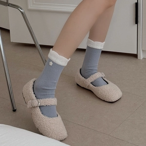 Women's vertical striped socks with lace trim and floral buttons worn with fuzzy flats