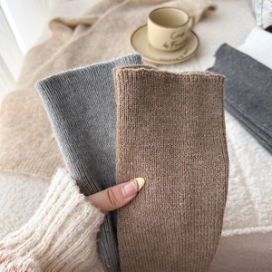 Detail of ribbed knit over-the-knee leg warmers in soft gray and brown wool textures