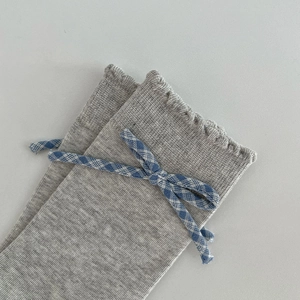 Close-up of gray cotton knit socks featuring a blue checkered bow and ruffled edge