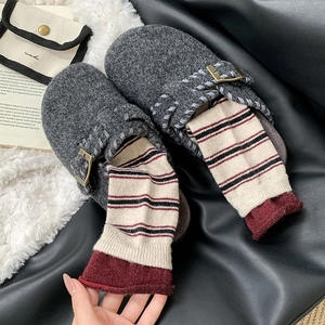 Détail de sabots en feutre gris avec boucle en métal et chaussettes rayées