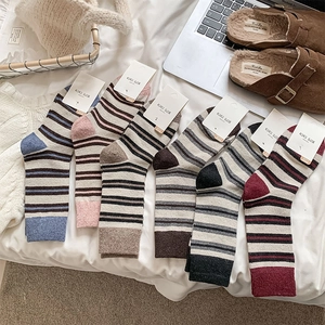 Close-up of multi-colored striped wool mid-calf socks arranged on white bedding