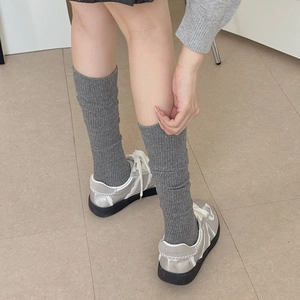 Close-up of grey ribbed knit knee-high socks paired with silver platform sneakers