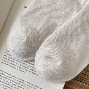 Detailed macro view of cream knitted wool socks with soft vertical striped texture