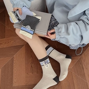Detail of sweet mid-calf socks with bow bear patch and blue-grey contrast cuff