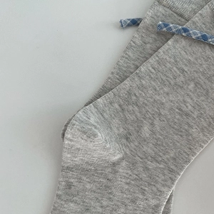 Close-up of grey ribbed knit socks featuring blue and white plaid ribbon detailing