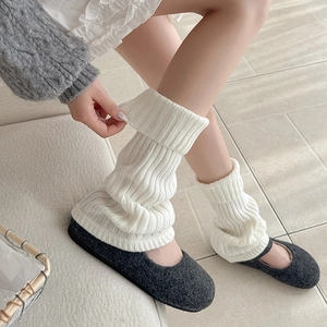 Close-up of white chunky knit leg warmers paired with grey Mary Jane ballet flats