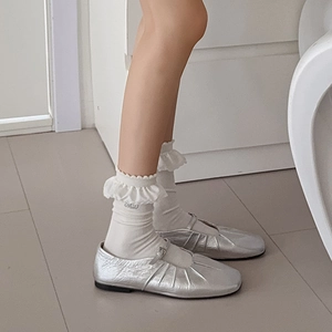 Dettaglio di scarpe Mary Jane argento con calze bianche con volant stile ballerina