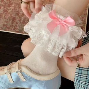 Detailed view of white tiered lace socks with a pink satin bow and mesh texture