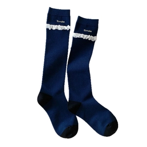 Navy knee-high socks with white lace trim and gold Smile embroidery on white background