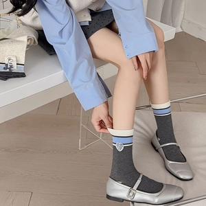 Detail of dark grey crew sock with striped cuff and blue plaid heart embroidery patch