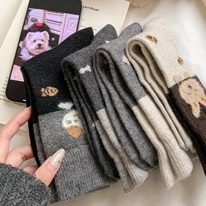 Gros plan de chaussettes en tricot épais avec motifs de chats et poissons brodés