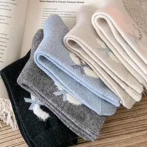 Detail of five pairs of thick knit crew socks in neutral tones with cross patterns