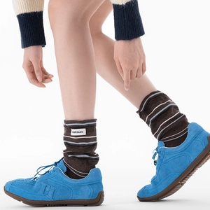 Chaussettes mi-hautes marron style preppy avec rayures et patch, portées avec baskets