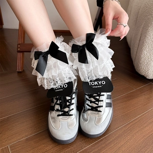 Detail of white lace socks with layered tulle ruffles and black satin ribbon bow accents