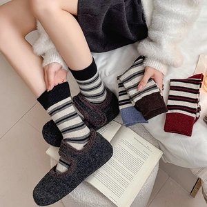 Close-up of cozy striped wool socks with grey fuzzy Mary Jane shoes in a home setting
